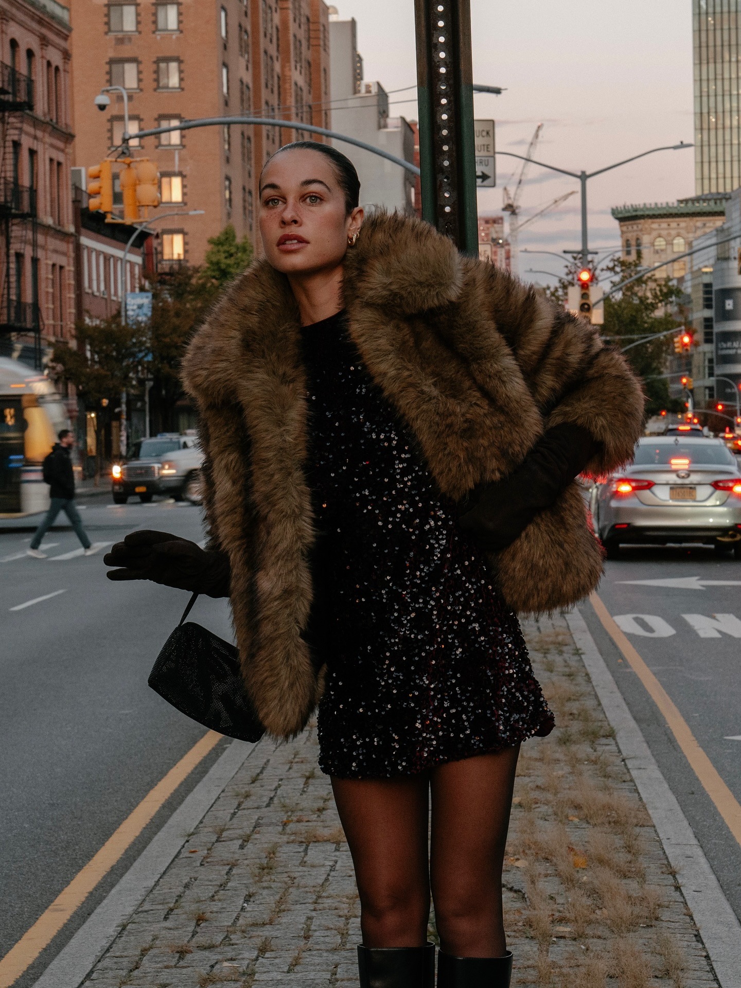 Fashion person Sarah Lysander wears a faux fur jacket outfit. She wears a black mini dress and a fur jacket.