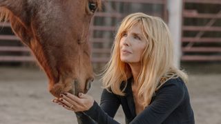 Kelly Reilly lightly holding a horses nose in Dutton Ranch.
