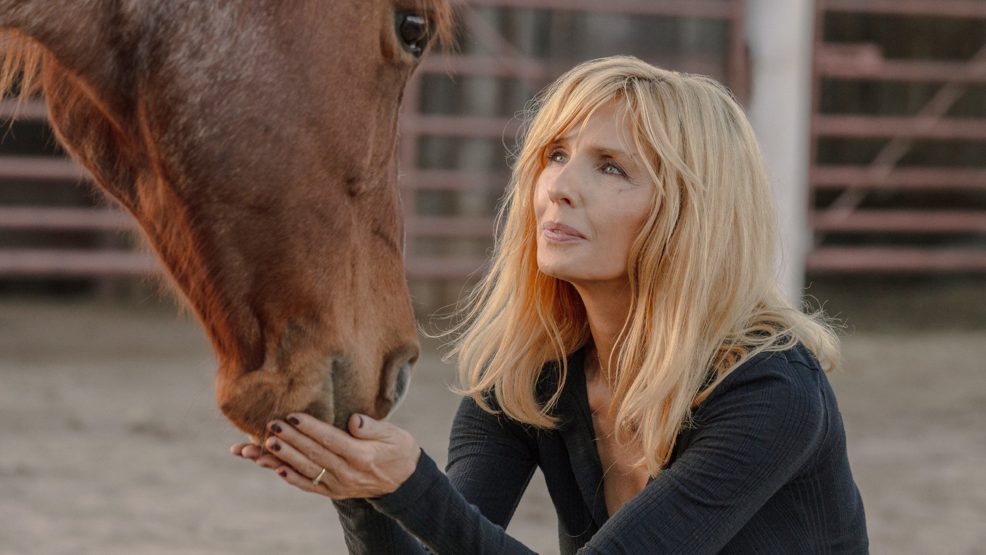 Kelly Reilly lightly holding a horses nose in Dutton Ranch.