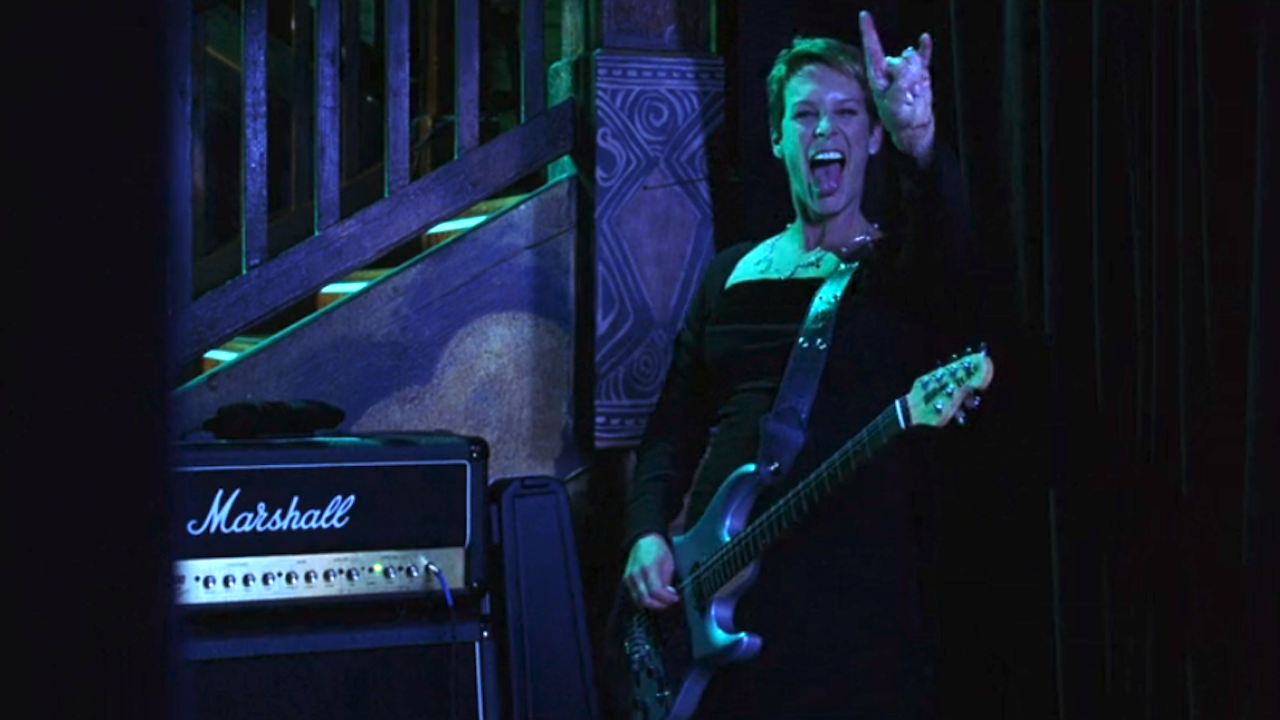 Jamie Lee Curtis doing rock on hand symbol backstage with electric guitar around her neck in Freaky Friday