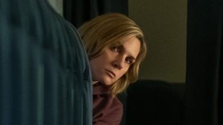 Carol peeking around seats from the back of an airplane in Pluribus Season 1