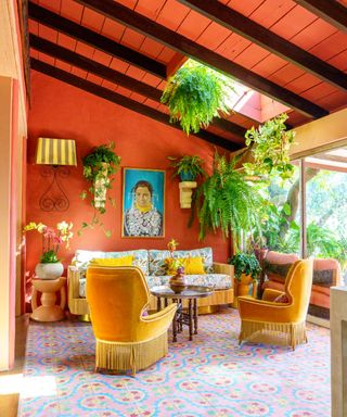 An orange and yellow living room with raftered wooden ceilings and a colorful area rug