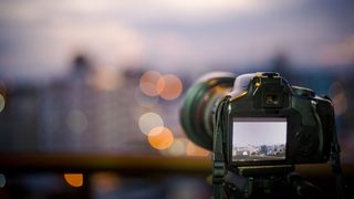 DSLR camera set up against sunset overlooking an out of focus city