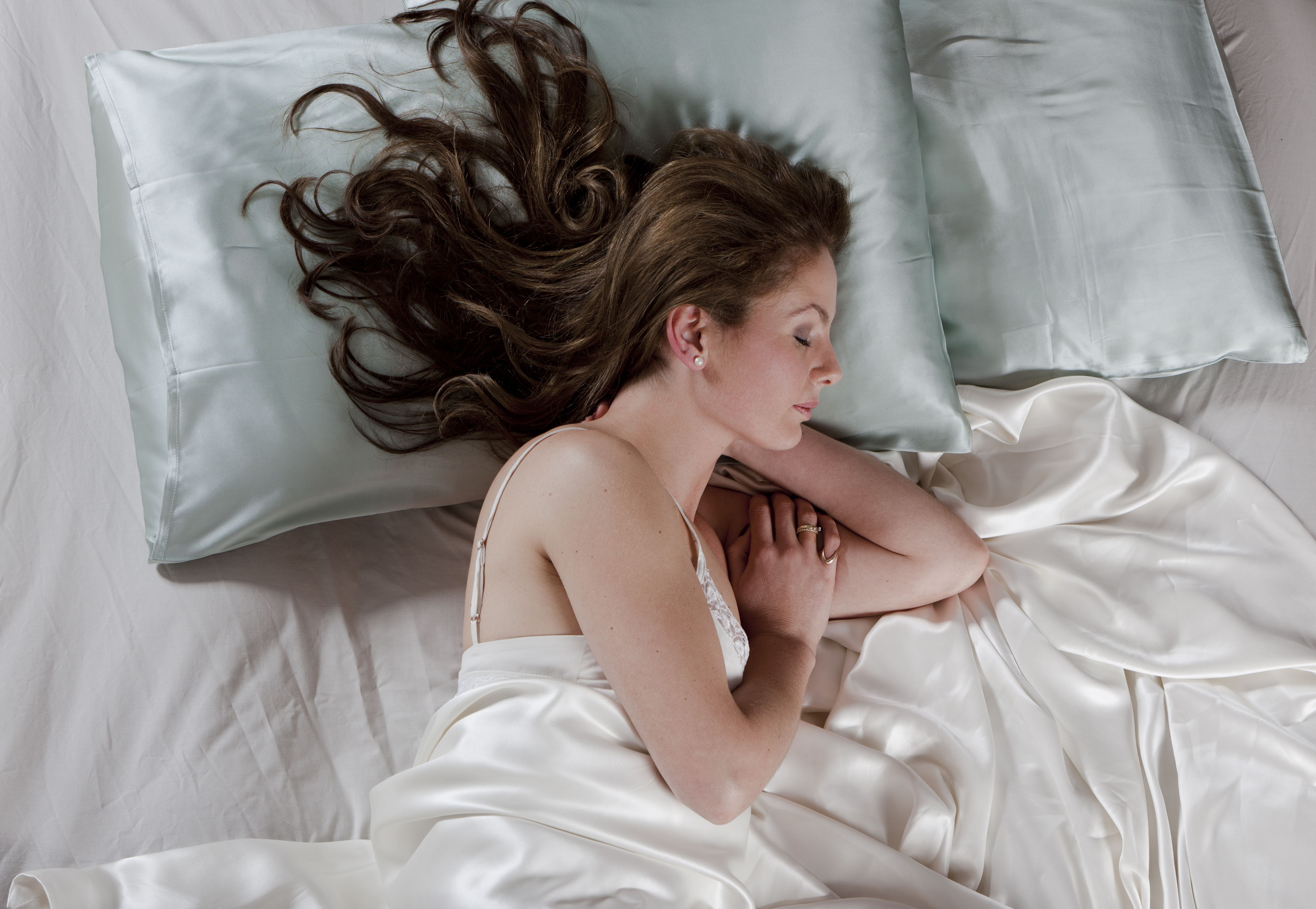 Woman sleeping on a silk pillowcase and bedding