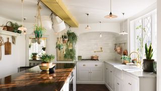 white kitchen with yellow beam, wooden worktop and lots of pendant lights
