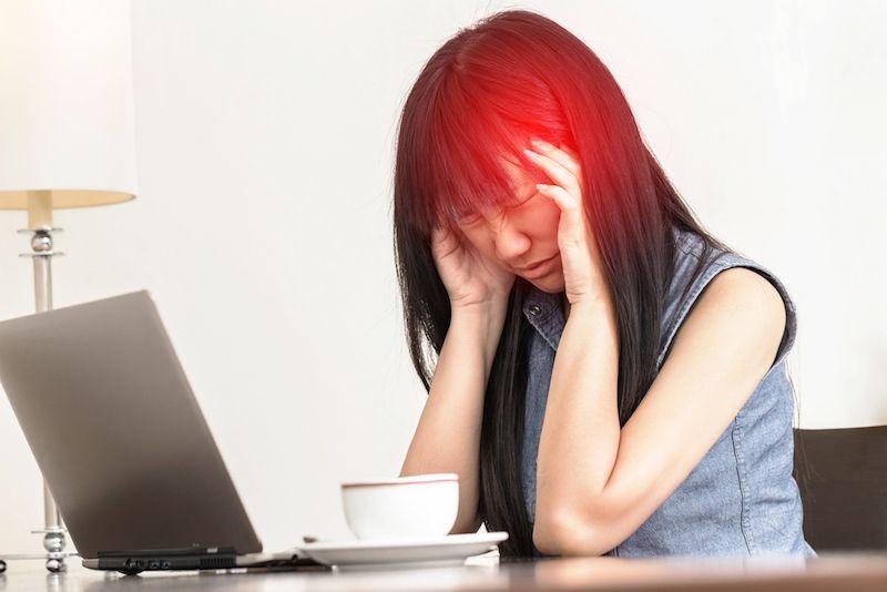 A woman rubs her head in pain.