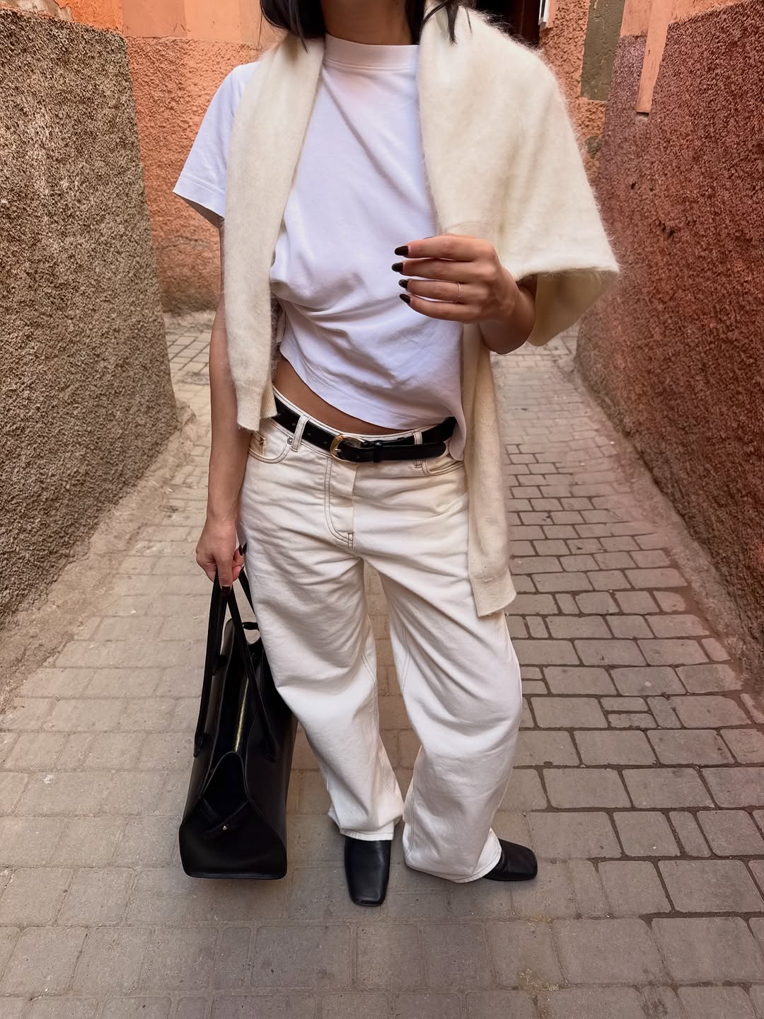 A woman wearing all white essentials, one of the biggest 2026 spring to summer transitional trends.
