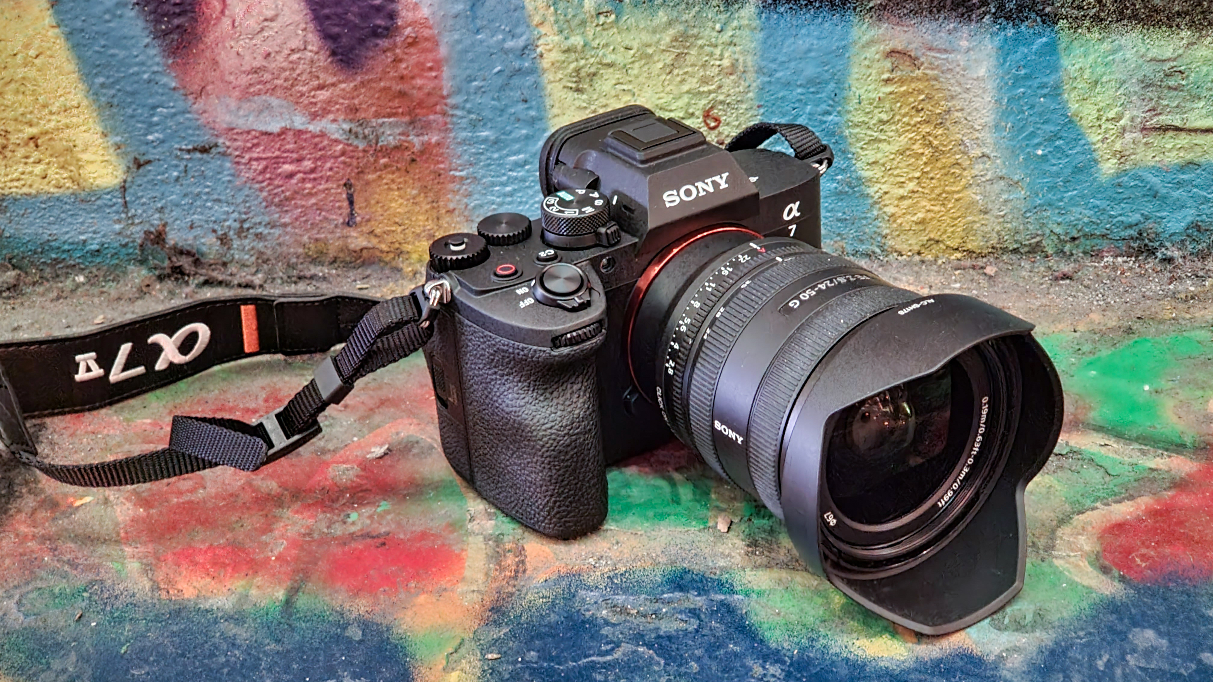 A photo of the Sony A7 V against a spray-painted multi-colored concrete wall.
