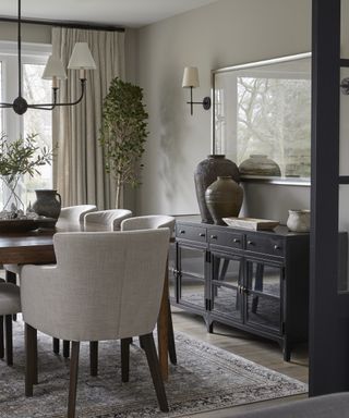 A neutrally toned dining room with dark wooden table and sideboard