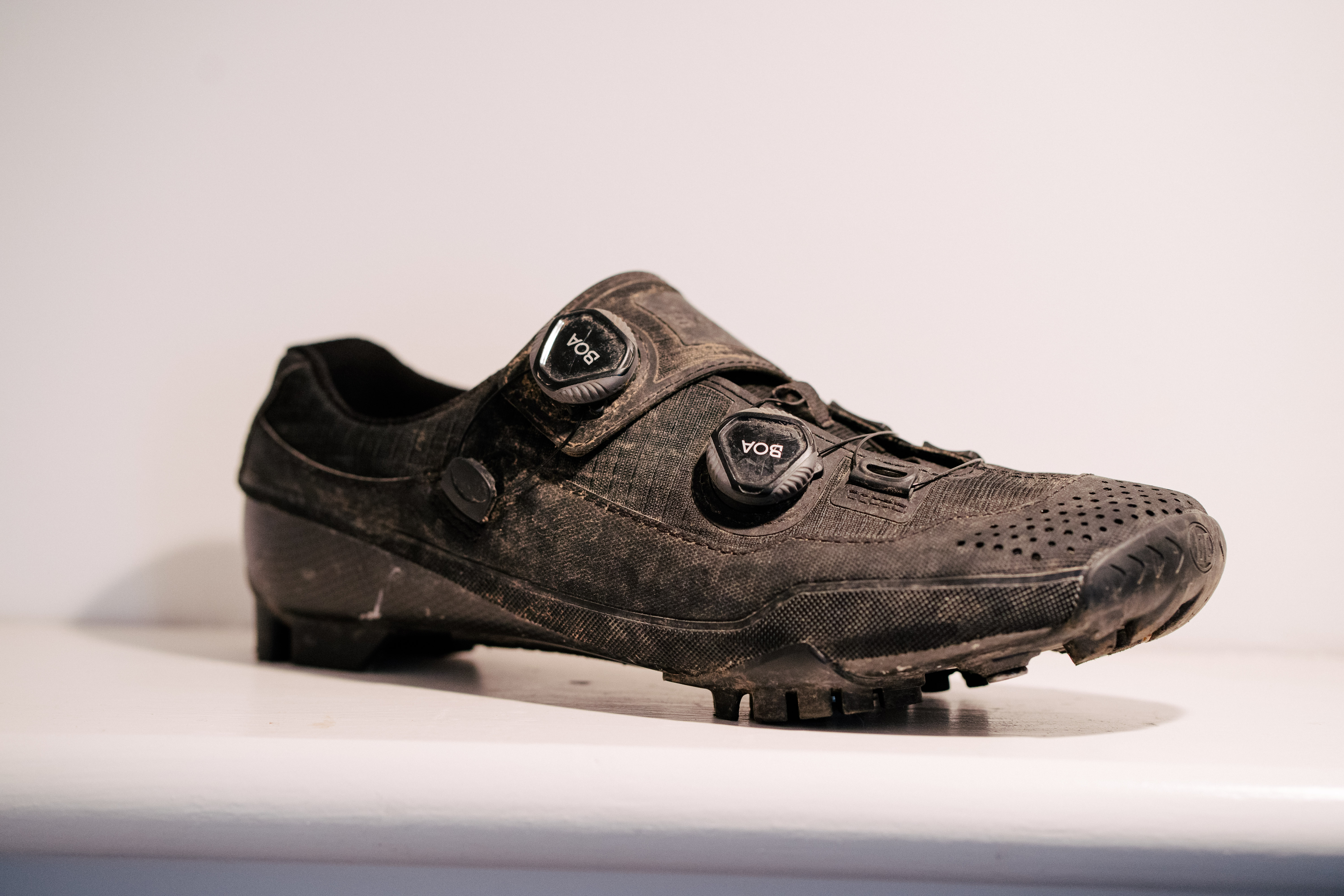 A black, muddy gravel shoe on a white shelf