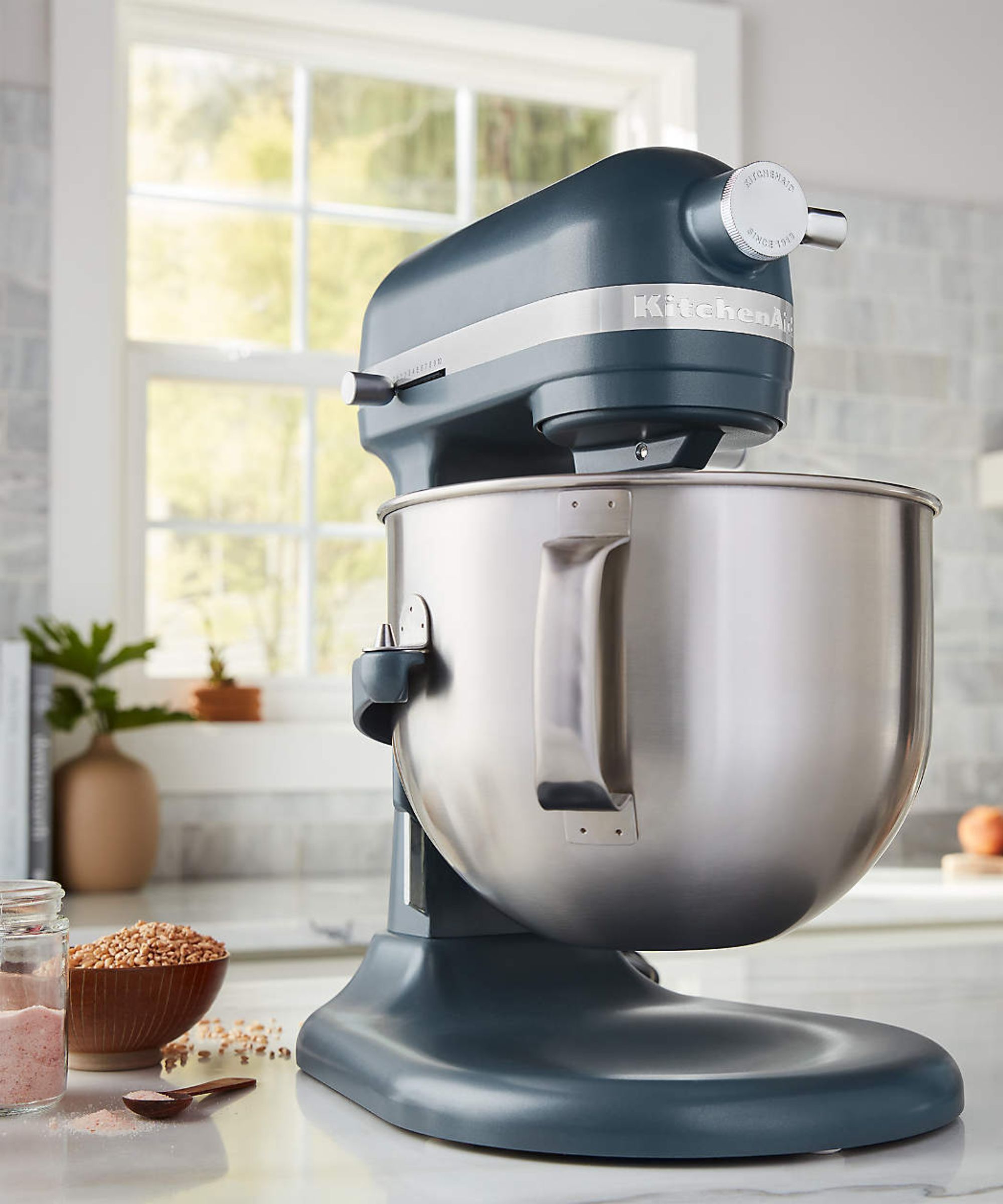 Teal KitchenAid mixer with silver bowl, in a white kitchen