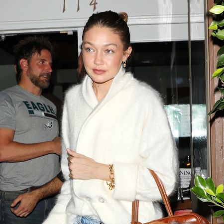 Bradley Cooper and Gigi Hadid skip the 2026 Golden Globes and go out on a double dinner date with friends at Italian restaurant Giorgio Baldi in Santa Monica. Gigi is wearing blue jeans, a white buttoned up coat sweater and carrying a Miu Miu leather handbag.