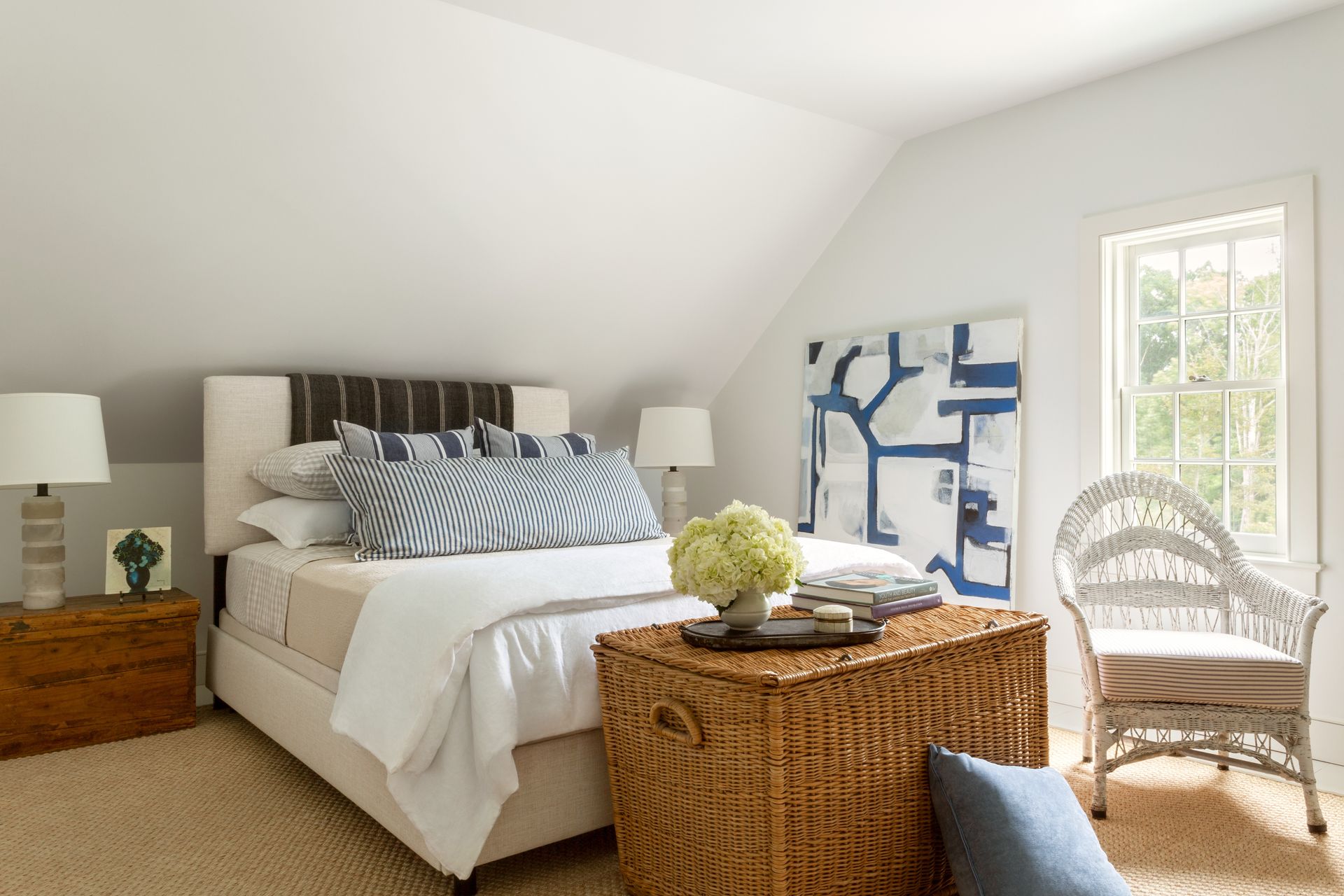 A diwan-style bed in a small, all-white room