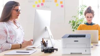 Two women working at a desk containing one of the best laser printers