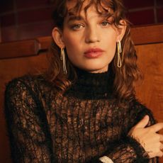 Model wearing a black mohair turtleneck and dangly earrings sold at Liberty London