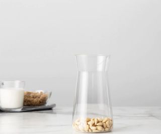Chef'n nut milk maker with cashews in the carafe and almonds and milk in the background