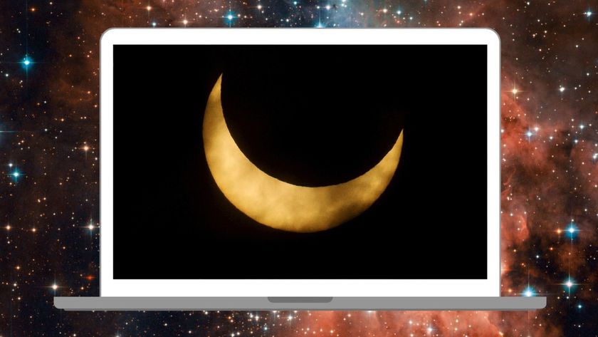 An image of the sun&#039;s disk during a partial solar eclipse. The moon&#039;s silhouette is blocking the entirety of the upper right section of the disk, leaving only its lower crescent visible, which is wreathed in thin clouds.