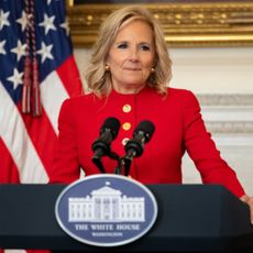 Jill Biden wearing a custom red schiaparelli suit while delivering an address at the white house