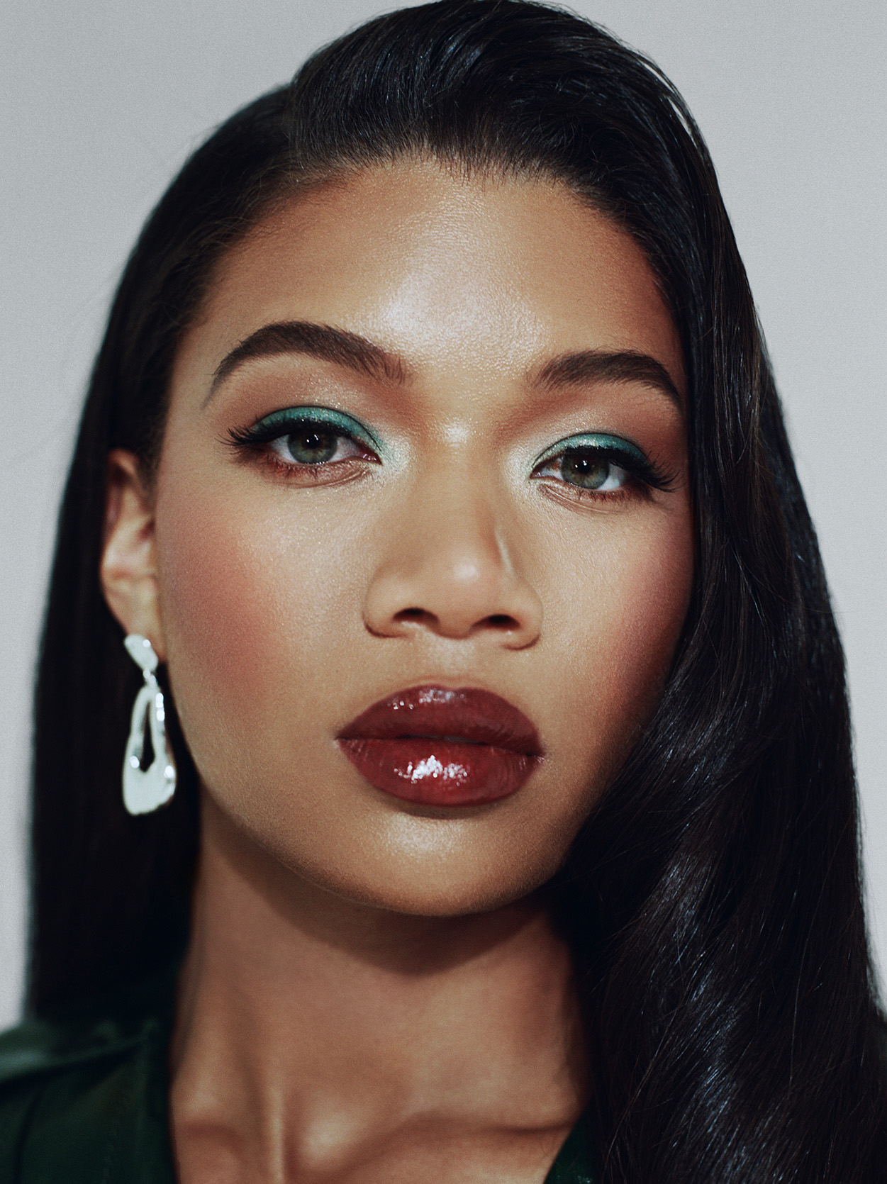 Lake Rucker in a close up shot wearing silver earrings red lipstick and green eyeshadow