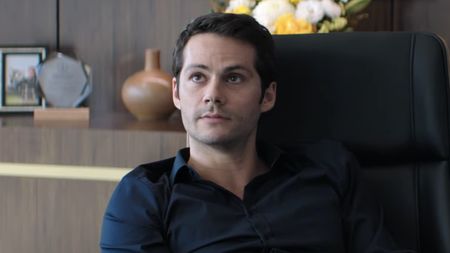 Dylan O'Brien's Bradley sitting behind desk in Send Help