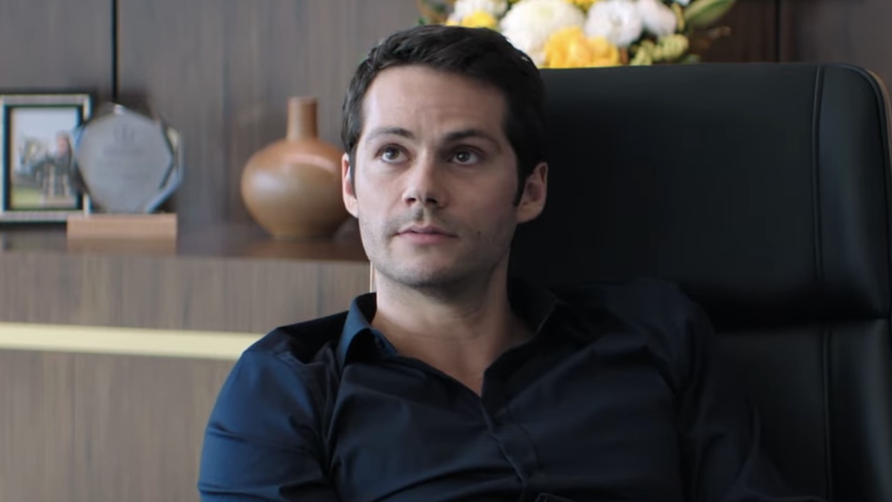 Dylan O'Brien's Bradley sitting behind desk in Send Help