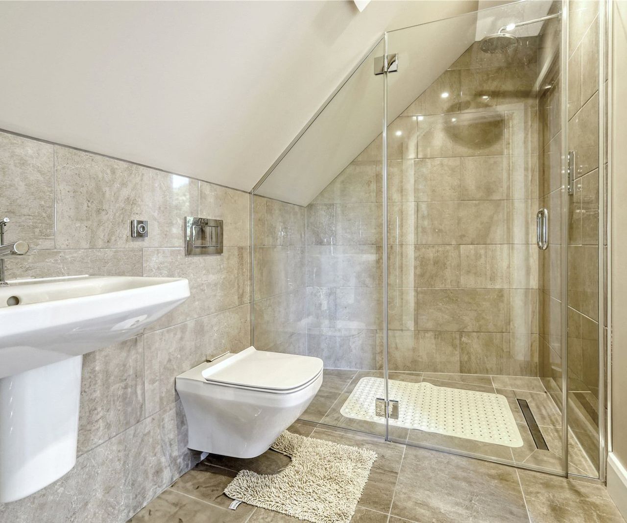 A slanted ceiling bathroom with white ceramic tiles and a walk in shower