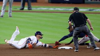 Yuli Gurriel #10 of the Houston Astros is tagged out at second base by Ozzie Albies #1 of the Atlanta Braves after trying to turn a single into a double during the eighth inning in game one of the World Series at Minute Maid Park on Oct. 26, 2021 in Houston, Texas.