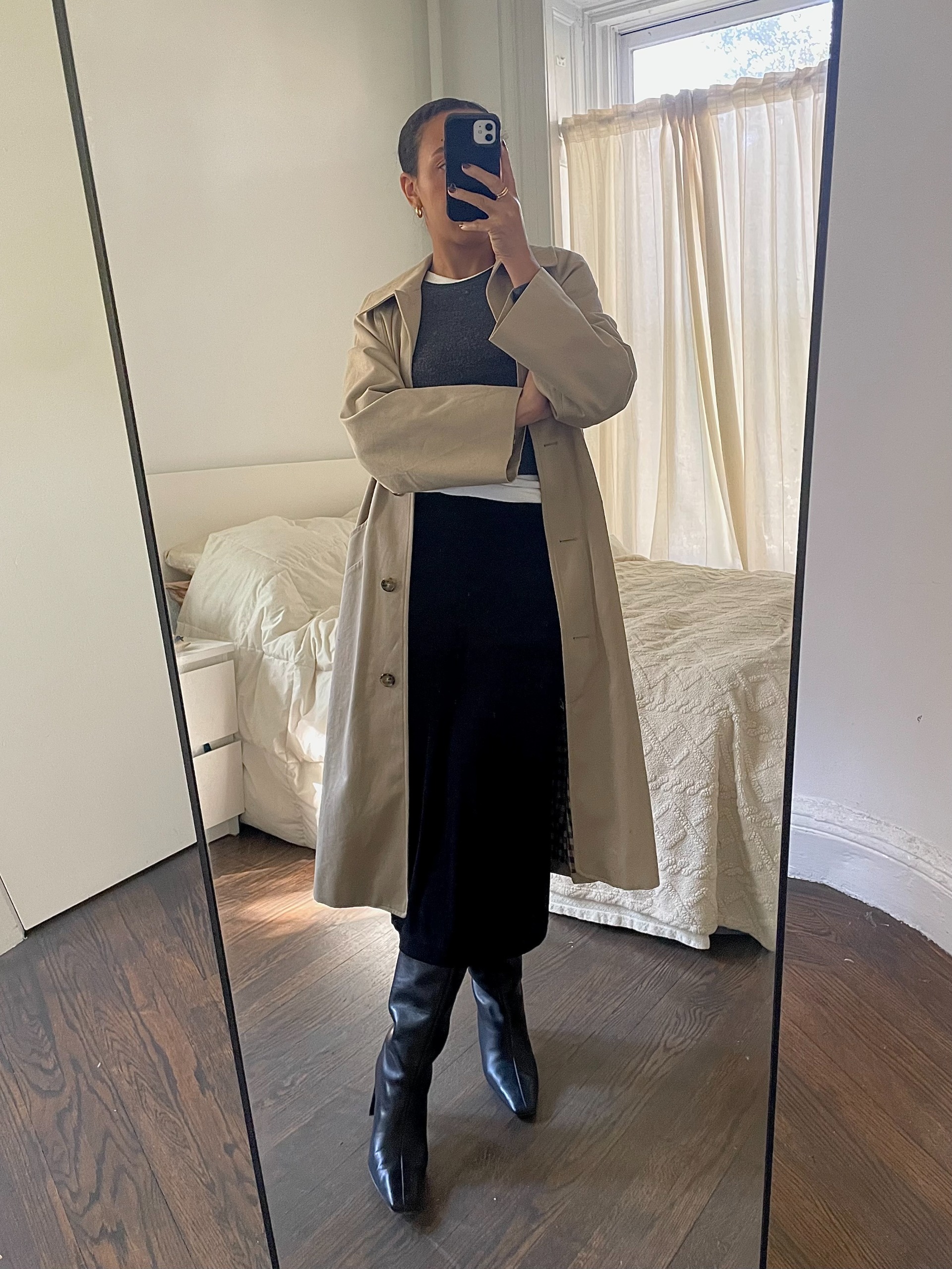Lauren Tappan wearing a trench coat, a black pencil skirt, a gray sweater, a white t-shirt, and black boots