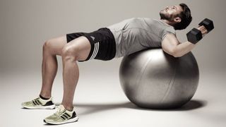 Man performs dumbbell flye on a gym ball
