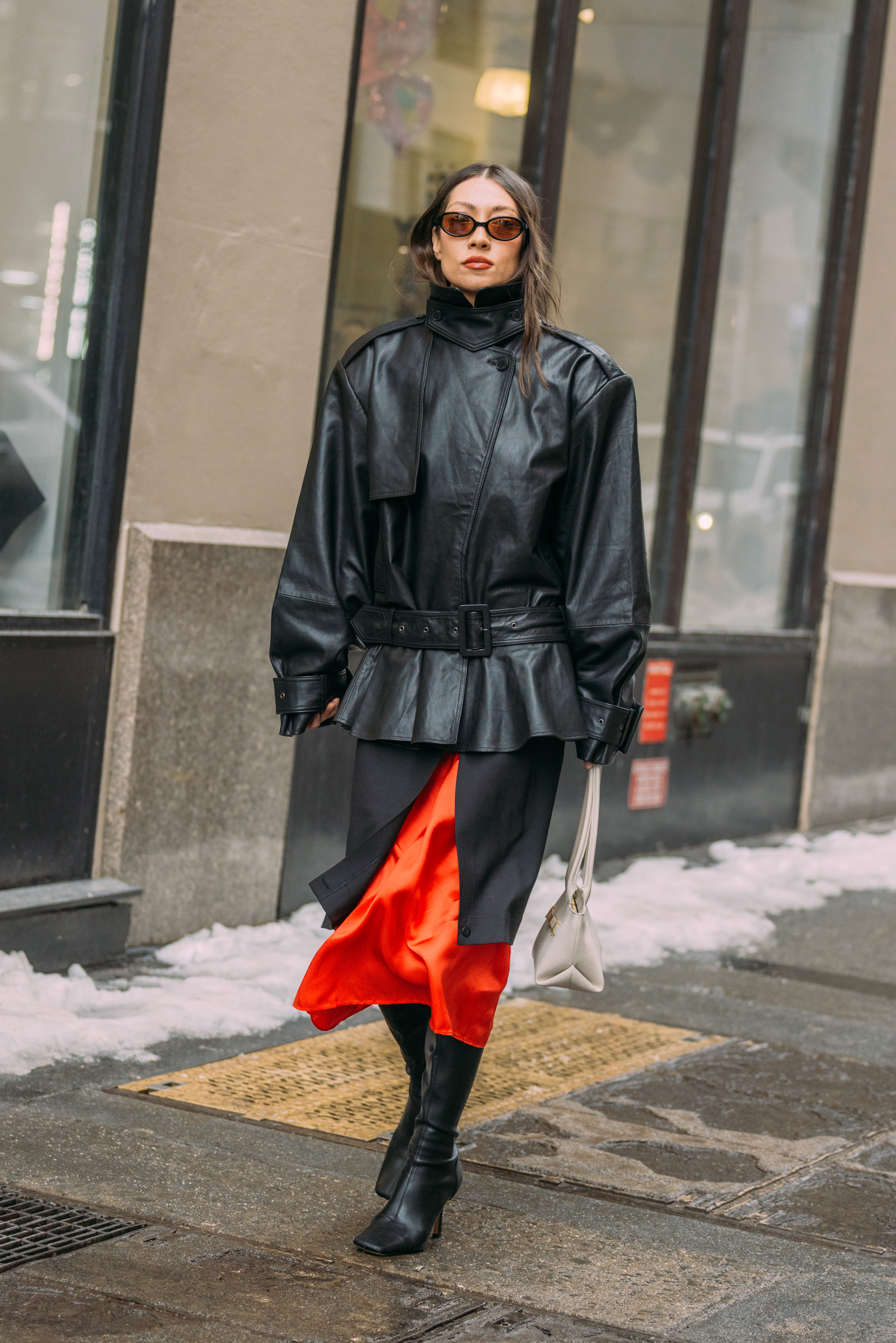 New York Fashion Week Attendee wears a peplum leather jacket with a calf-length skirt and knee-high boots.