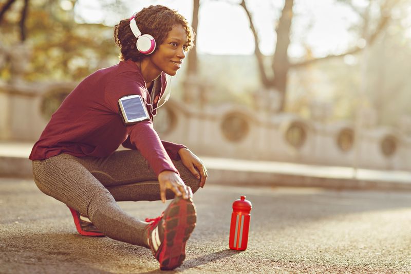 A female runner crouches down to stretch in the street