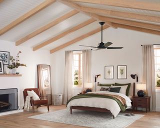 bedroom with white walls, wood ceiling beams, cozy bedding