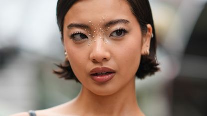 A woman at fashion week with strong eyebrows illustrating a guide to the best brow pens of 2024