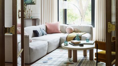 Off-white L-shaped sofa in a living room with round coffee table and patterned rug