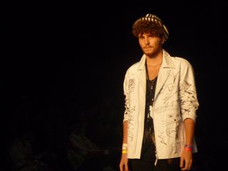 Male model wearing an open, white jacket with the sleeves pulled up, and a black and white striped hat
