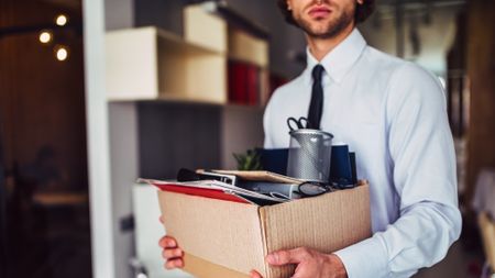 Man carrying a cardboard box of desk supplies