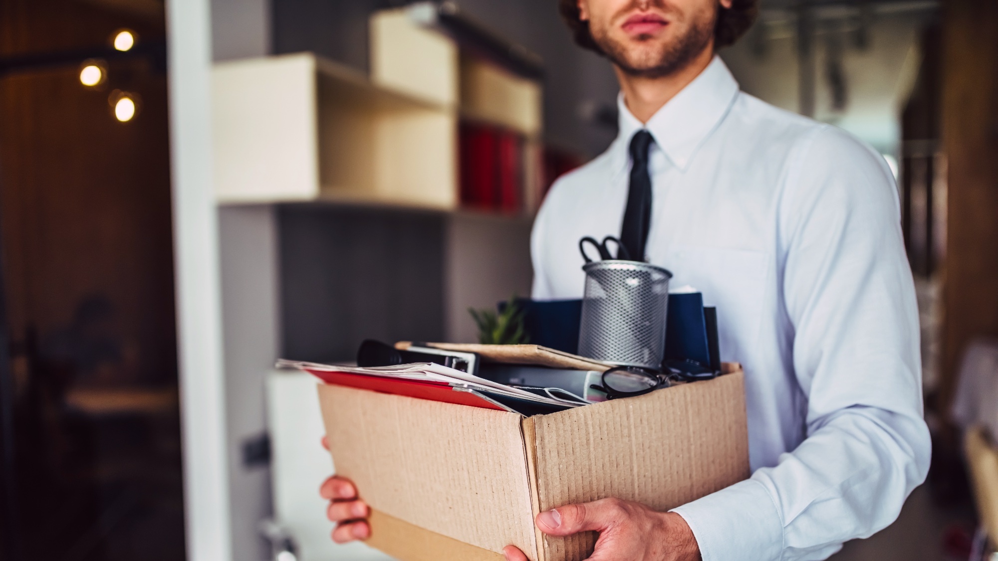 Man carrying a cardboard box of desk supplies 