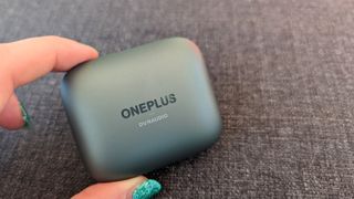 OnePlus Buds Pro 2 review: headphones charging case held in hand with green nails