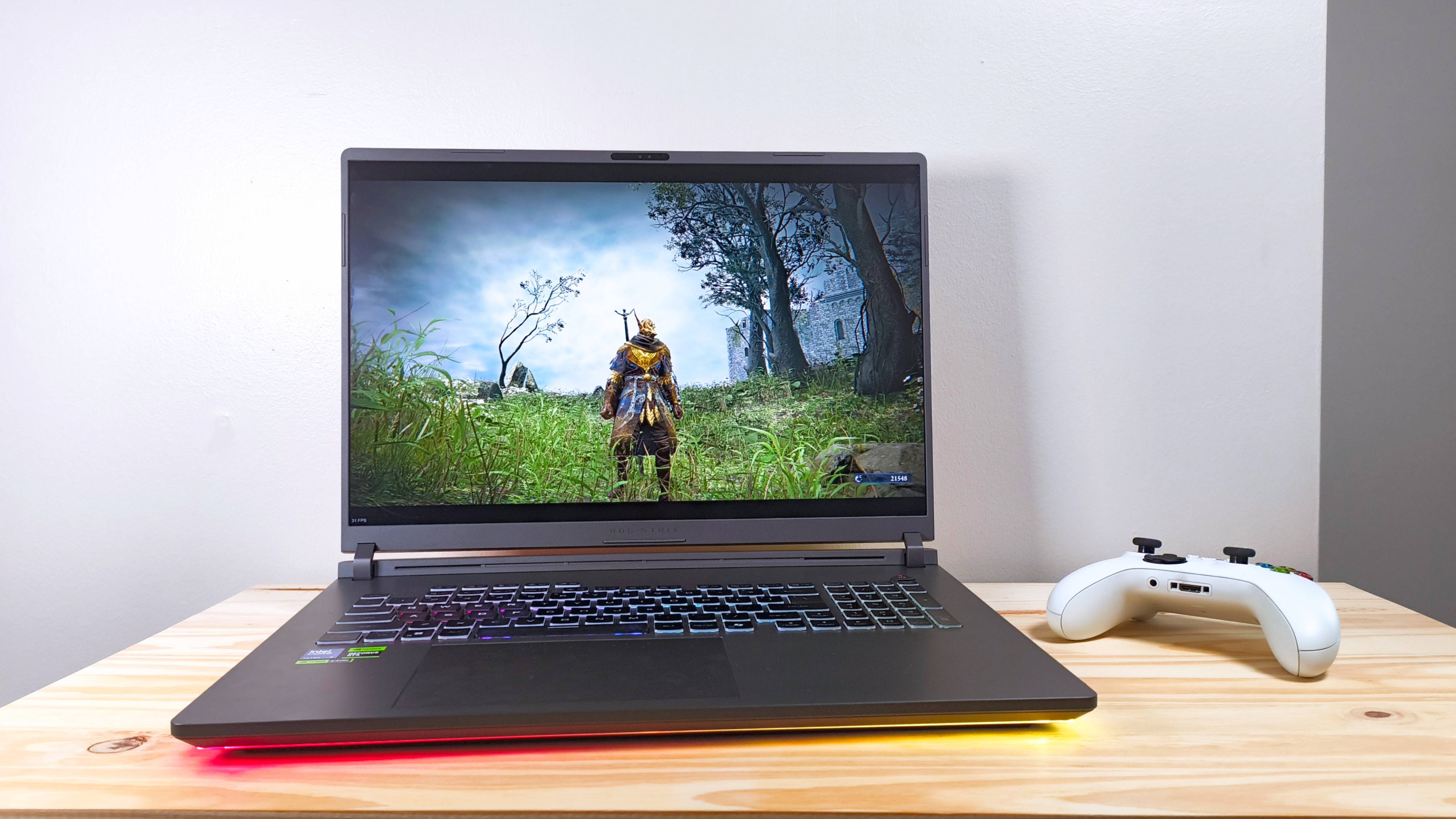 The Asus ROG Strix G18 running Elden Ring Nightreign on a wood table beside a white Xbox controller