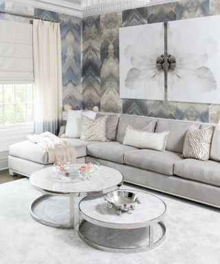 Glam living room with painterly tonal gray wallpaper and large scale floral wall art, and round metal nested coffee table.