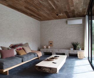 An air to air heat pump indoor unit on an exposed painted brick wall in a room with seating