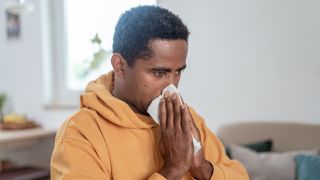 Man blows his nose with a tissue