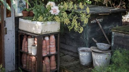 wormery for compost in a garden beside terracotta pots
