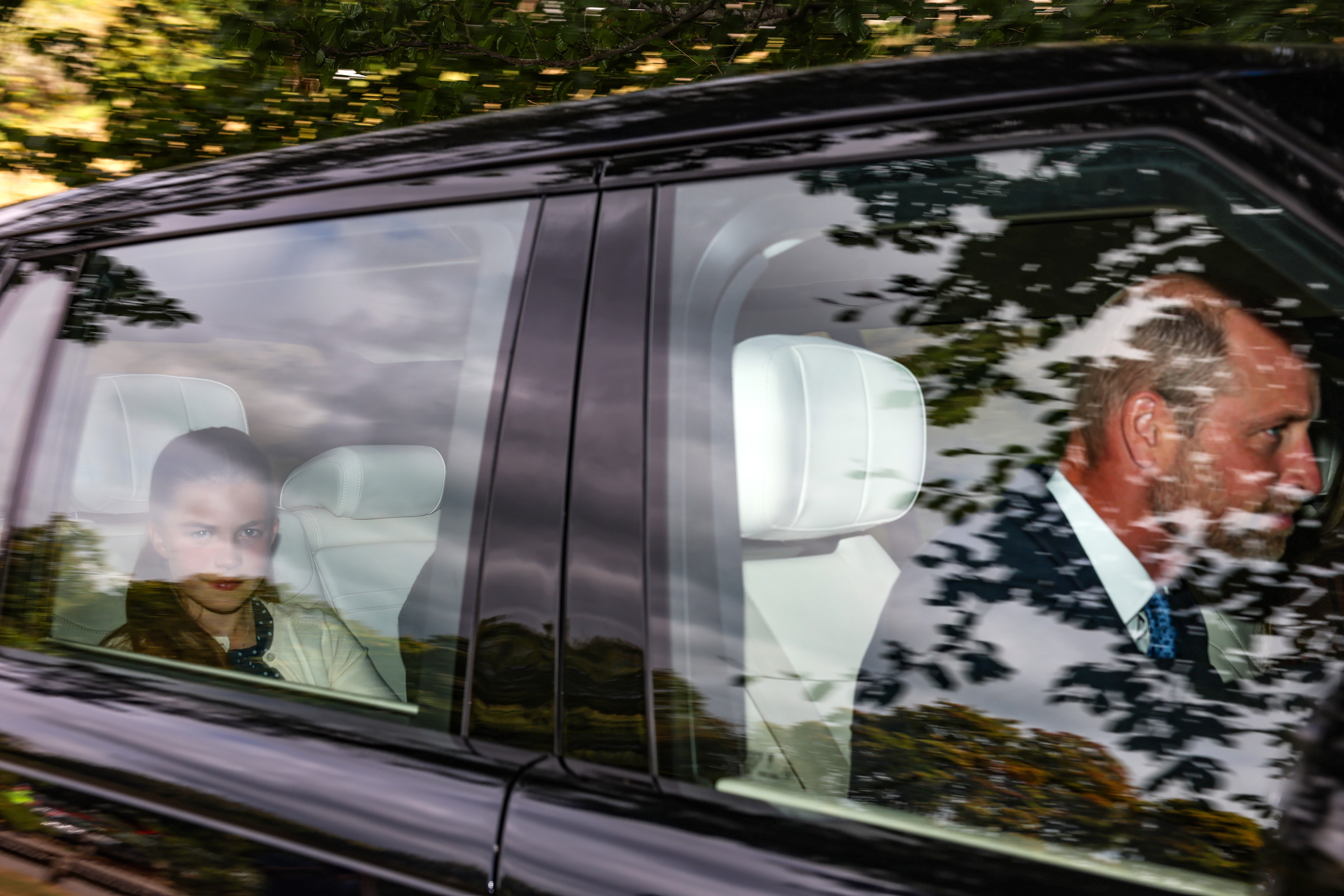 Princess Charlotte riding in the backseat of a car with Prince William driving