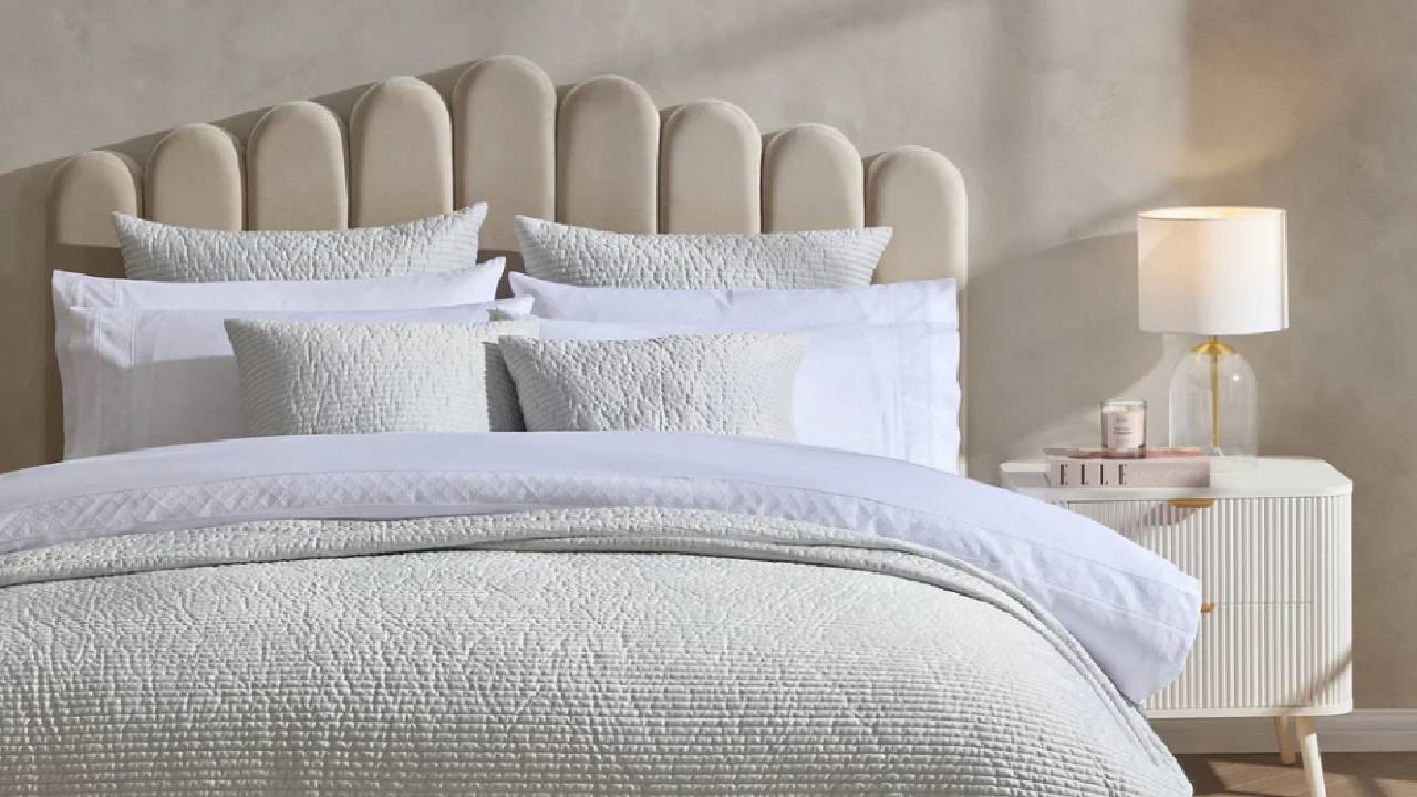 A neutral, beige, bed with textured, cream bedding from Dusk in a modern, minimalist bedroom. 
