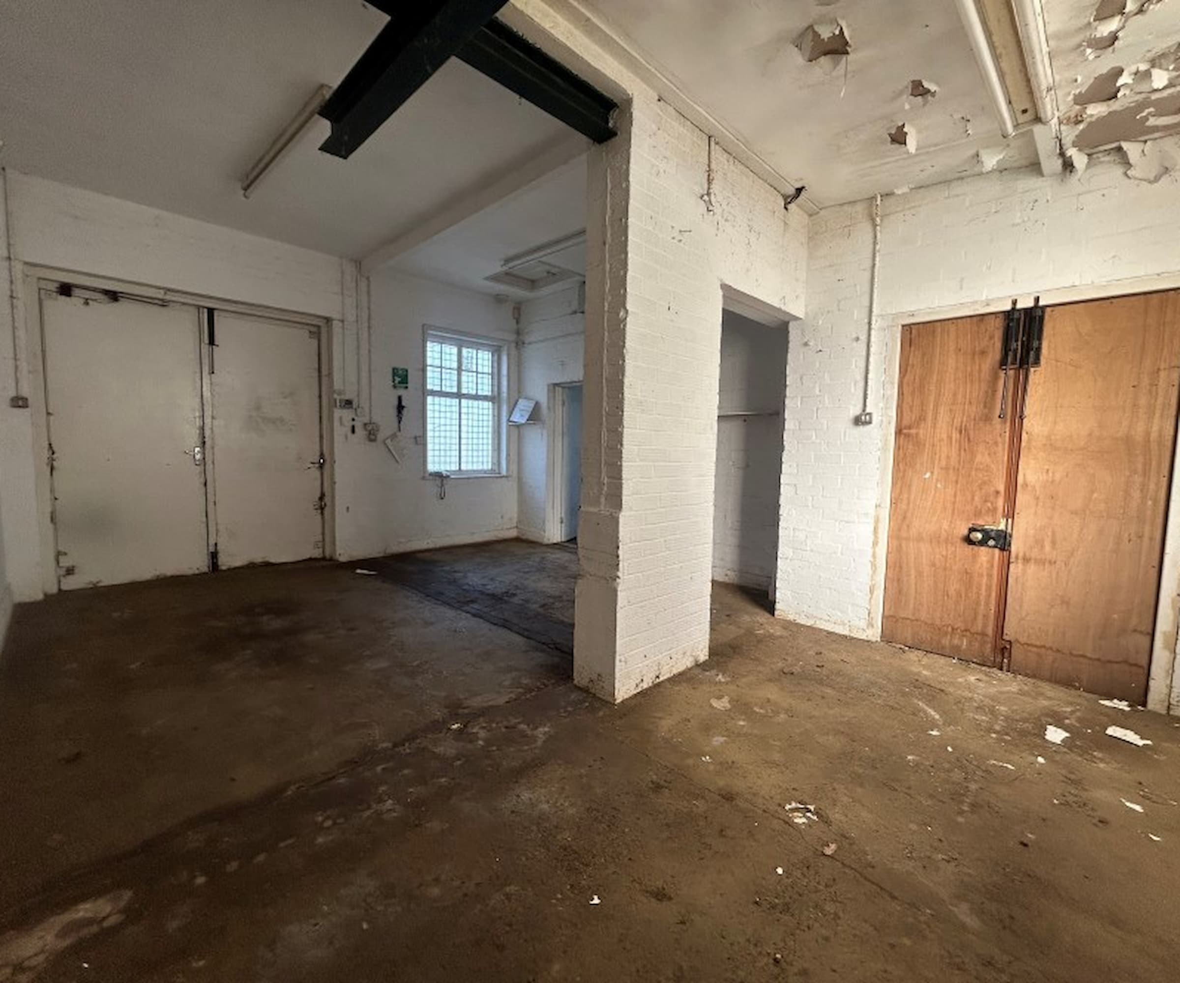 Inside a mortuary with wooden doors and part of a brick wall breaking up the room