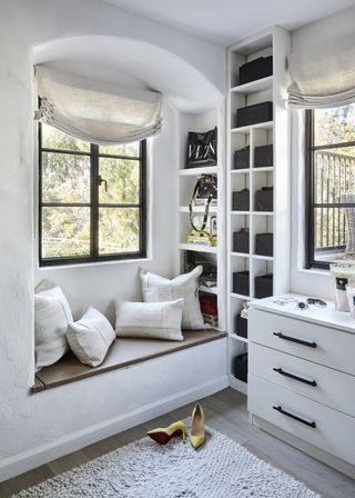 dressing room with window seat and two windows and open shelves and chest of drawers