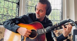Robin Nolan plays a Gibson acoustic into a mic as he records at home.