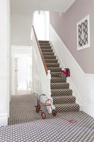 Hallway and staircase with white walls and neutral colour above dado and spotted grey carpet