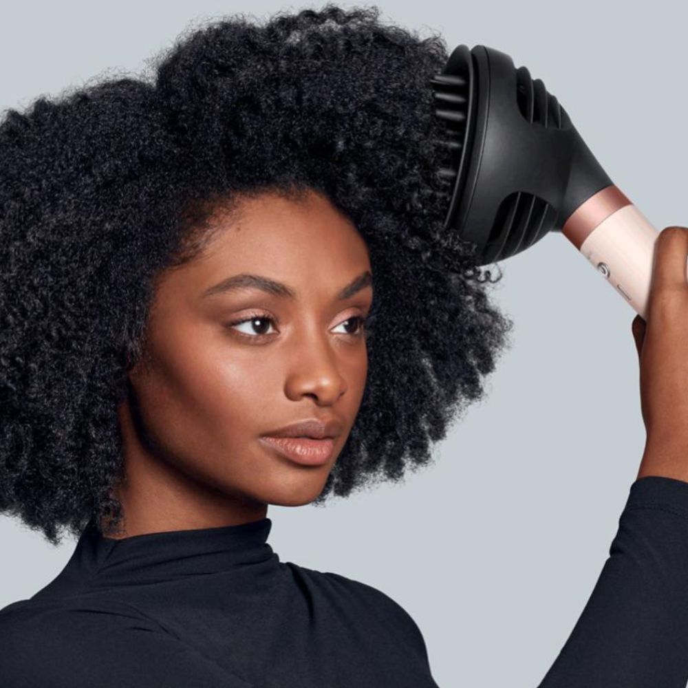 Woman dressed in black using Dyson multi-styler on her curly hair